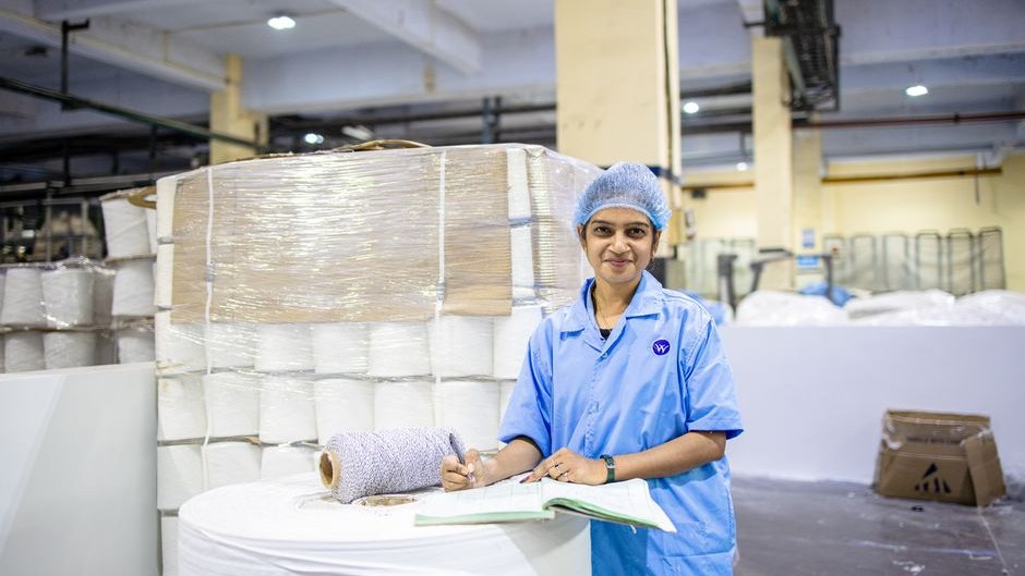 A factory worker inspects a product on a conveyor belt highlighting the slow and error-prone nature of manual quality checks in manufacturing AI quality control