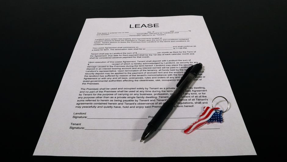 A tenant reviews a lease agreement on a phone, surrounded by AI-generated rental images that look real but are misleading
