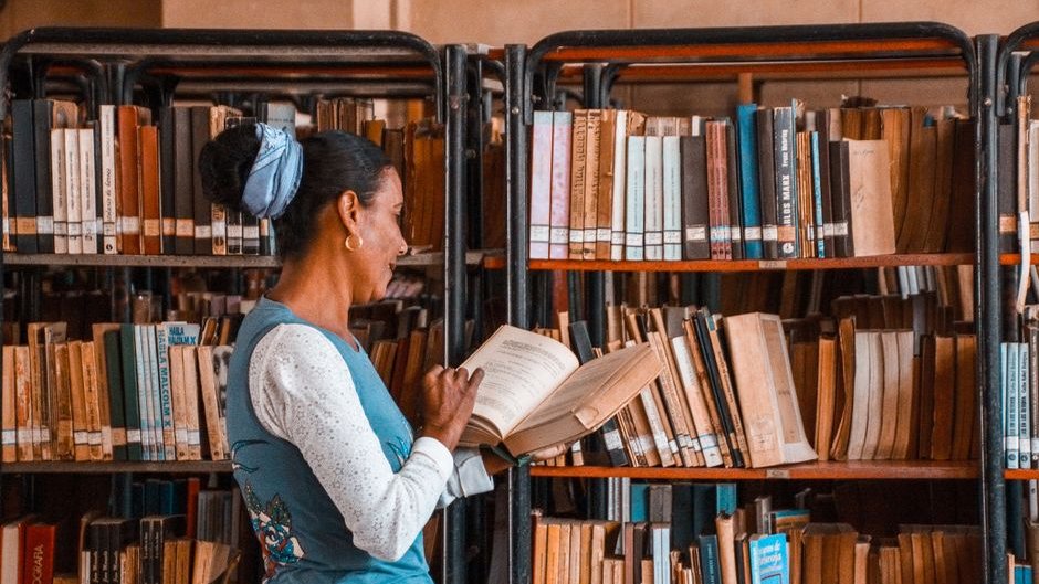 A stack of well-researched non-fiction books sits beside a screen displaying poorly written AI-generated text