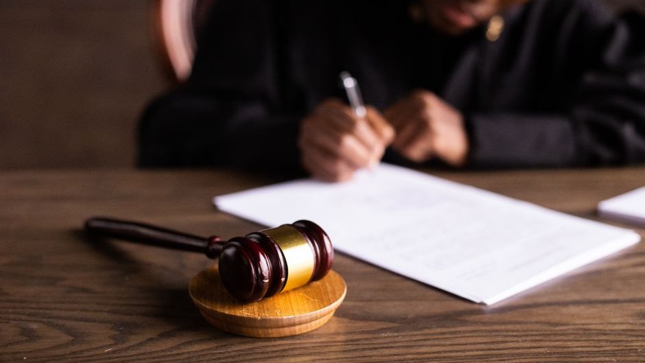 Overflowing legal documents pile high on a tribunal desk creating AI legal system overload