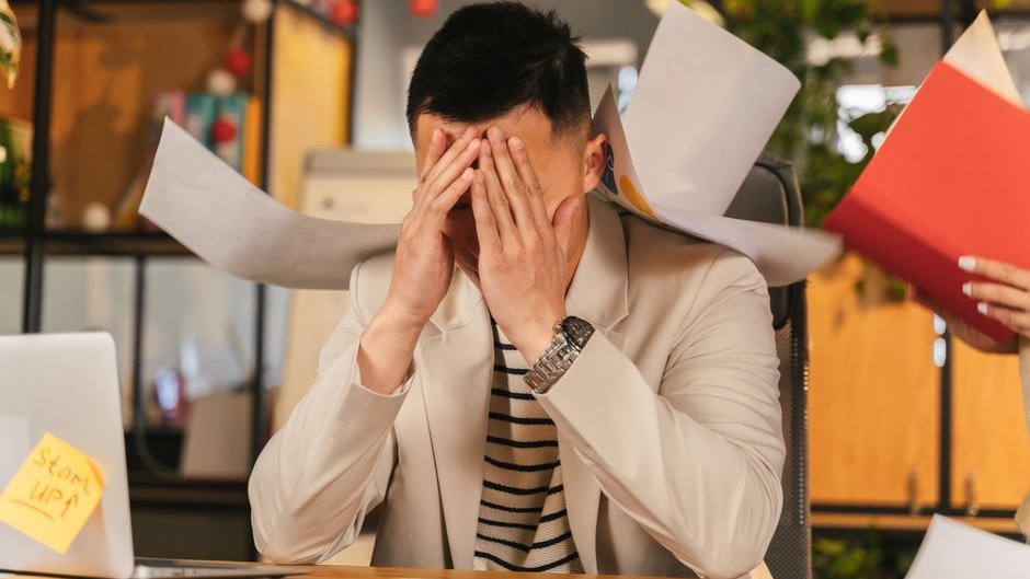 Stressed manager surrounded by overflowing paper files during an AI legal system overload