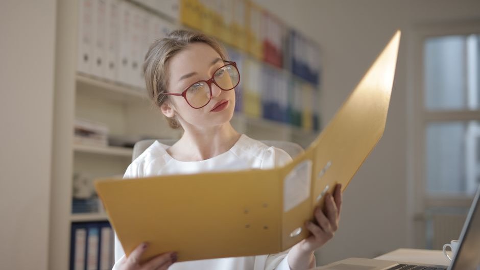 An auditor examines flagged compliance reports on a monitor highlighting AI vendor deception