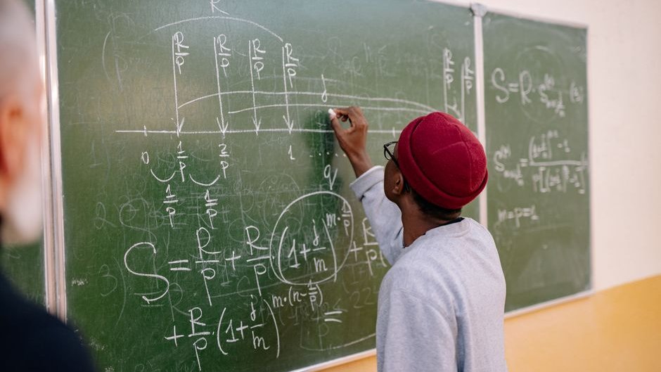 Researcher writing handwritten proofs on a chalkboard highlighting mathematics in the age of ai